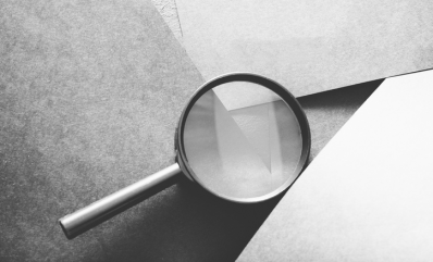 A magnifying glass placed on top of grey layered paper. ©Getty Images 